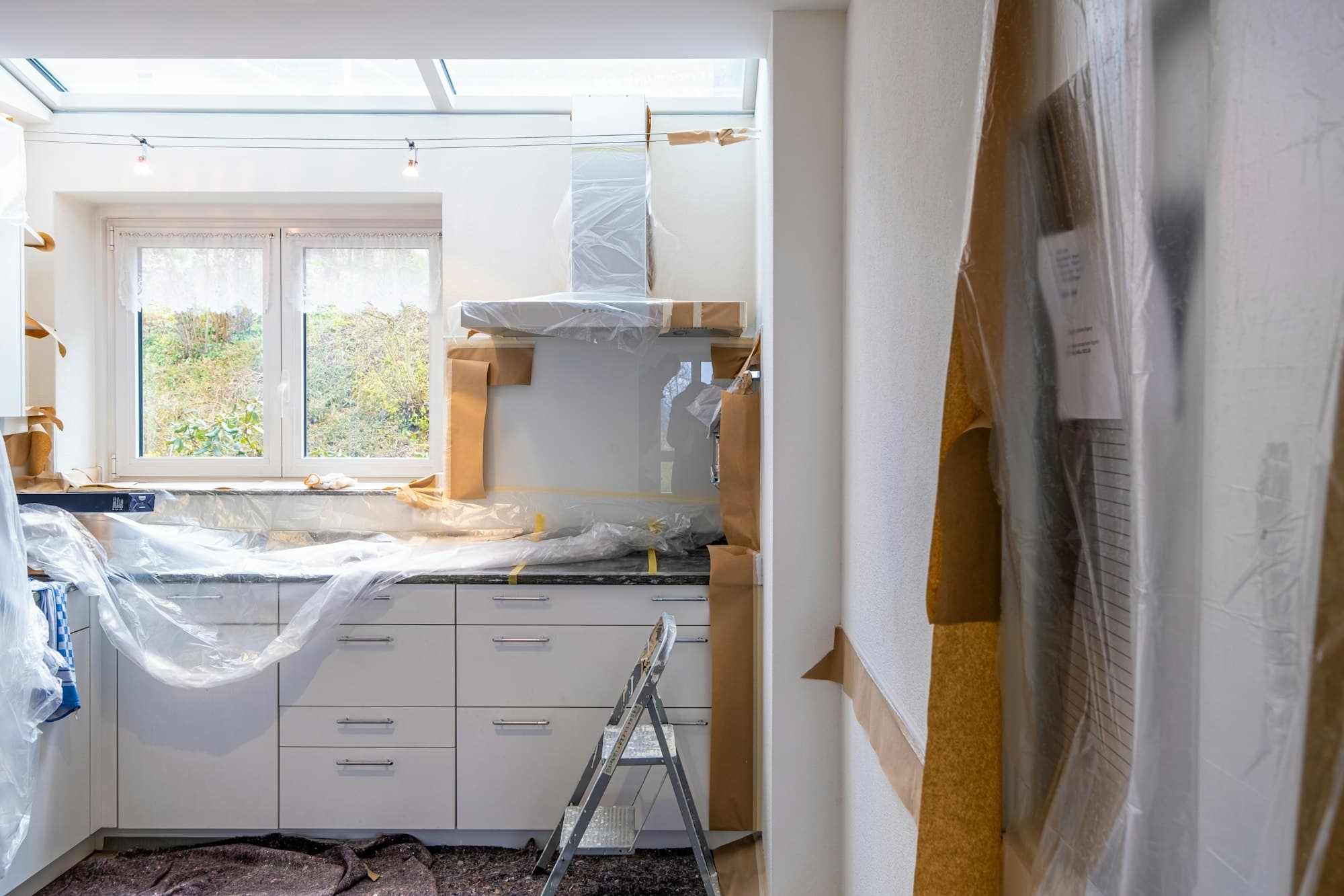 Kök under renovering med täckt inredning och stege